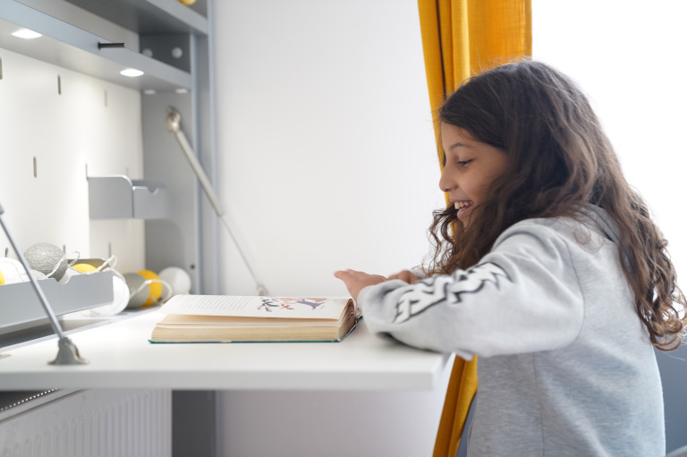 Retractable child's desk unfolded with a child working on his desk.