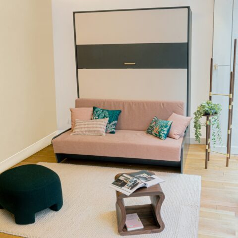 Salon avec un lit armoire Reverso basalte et blanc fermé avec un canapé