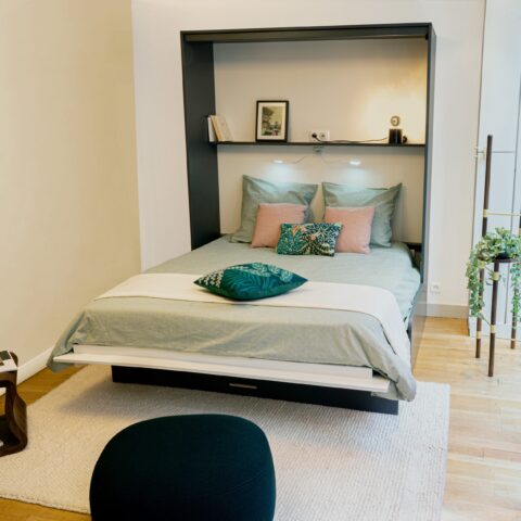 Salon avec un lit armoire Reverso basalte et blanc ouvert avec un canapé
